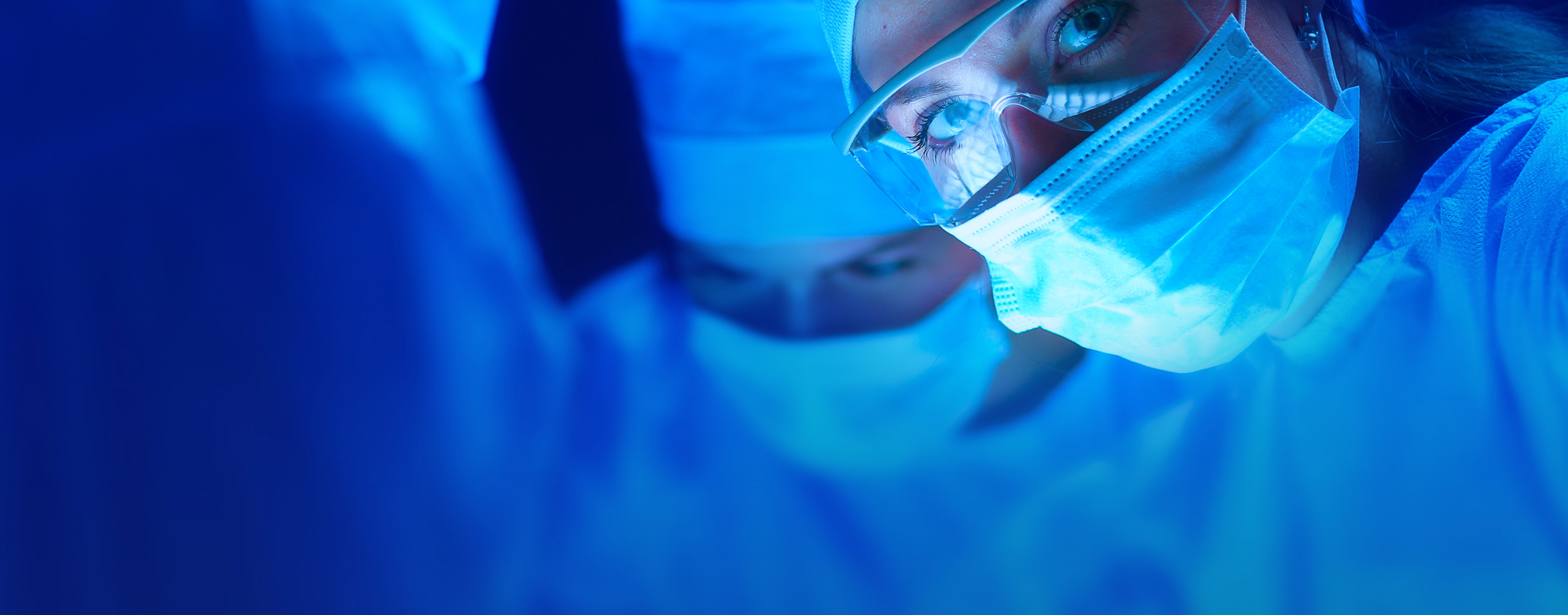 Masked doctor staring forward with blue background.